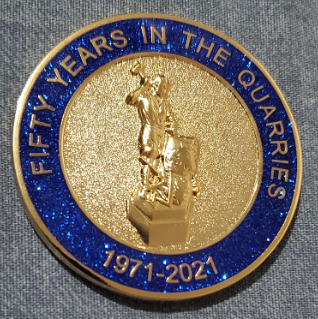 Coin, blue outline, gold color. Fifty Years in the Quarries text, front